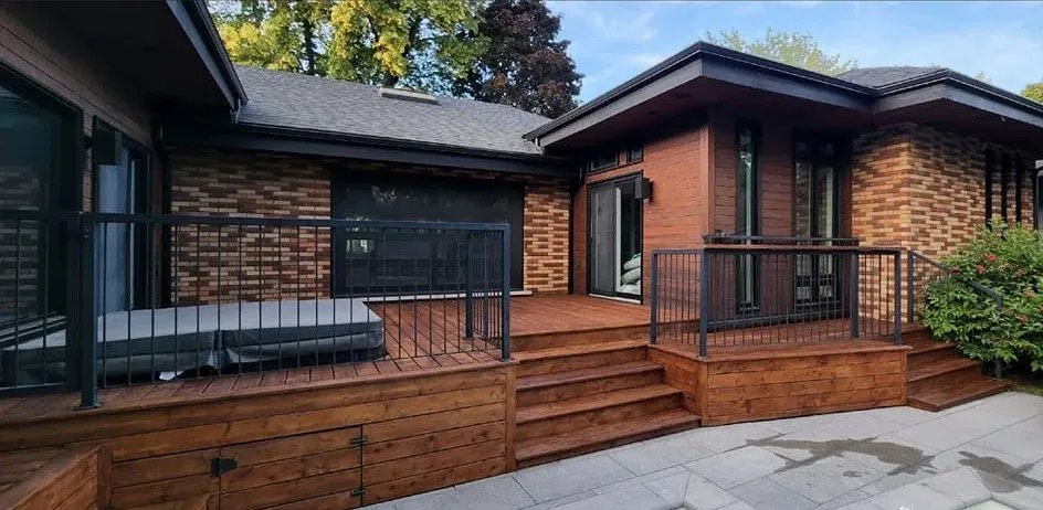 Terrasse en bois fraîchement teinte avec spa, devant une maison de brique — Teinture Bois'Elle