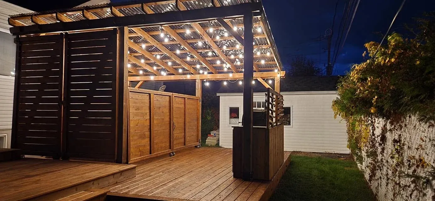 Terrasse en bois avec pergola illuminée de guirlandes lumineuses, le soir — Teinture Bois'Elle