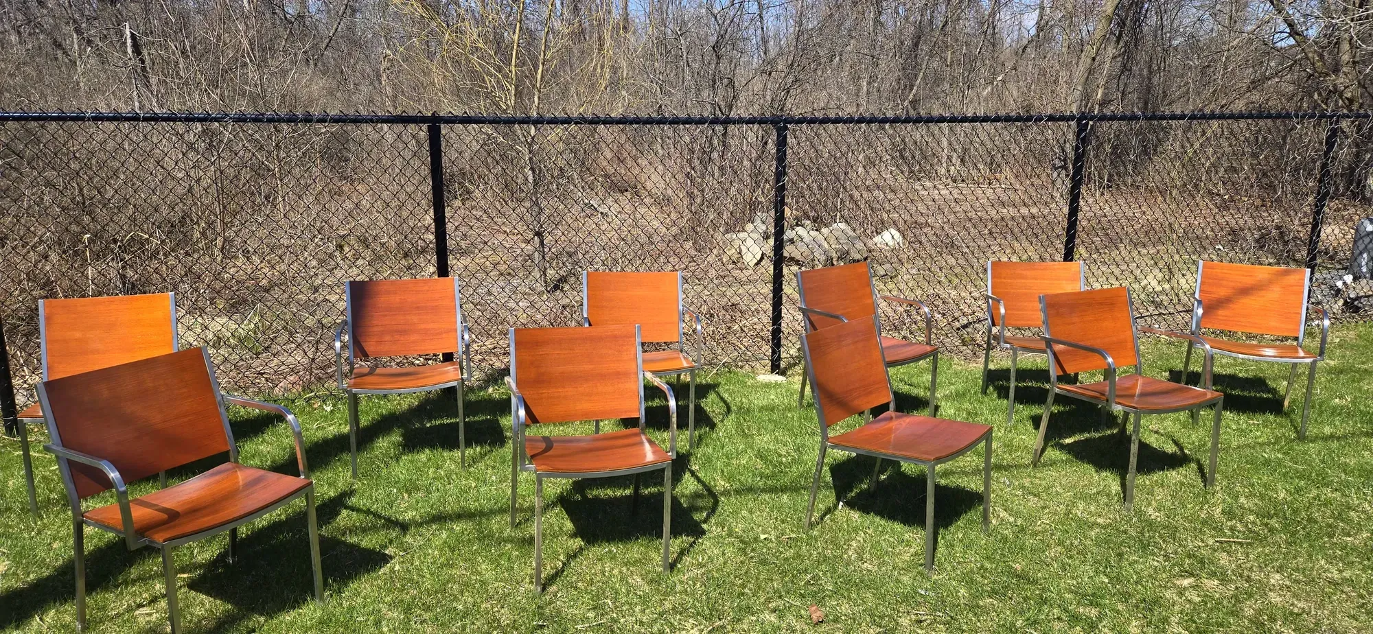 Ensemble de chaises en bois teint restaurées, alignées à l’extérieur après finition